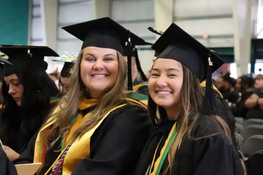 two smiling students at graduation